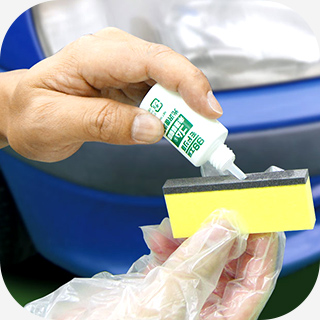 手袋をつけ、専用スポンジを切り離しスポンジの黒い面に光沢復活剤の液を適量染み込ませ、劣化したバンパーの未塗装樹脂部分に薄く均一に塗り広げます。