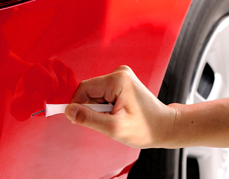 付属のヘラを使ってパテをバンパーのキズに押し込むようにならします。